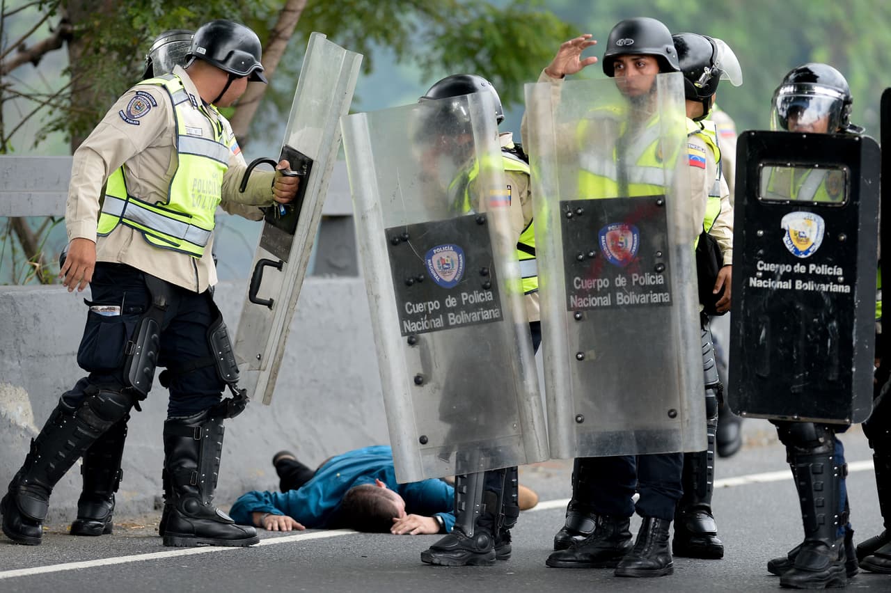 Un manifestante herido en el piso, junto a la policía antidisturbios.