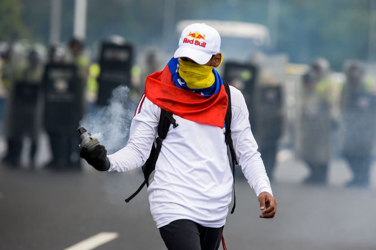 Los jóvenes manifestantes toman las bombas lacrimógenas disparadas por la policía y las regresan.