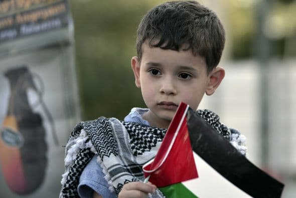 Un niño sostiene una bandera palestina cerca de la embajada israelí en Atenas durante una manifestación contra los ataques israelíes.