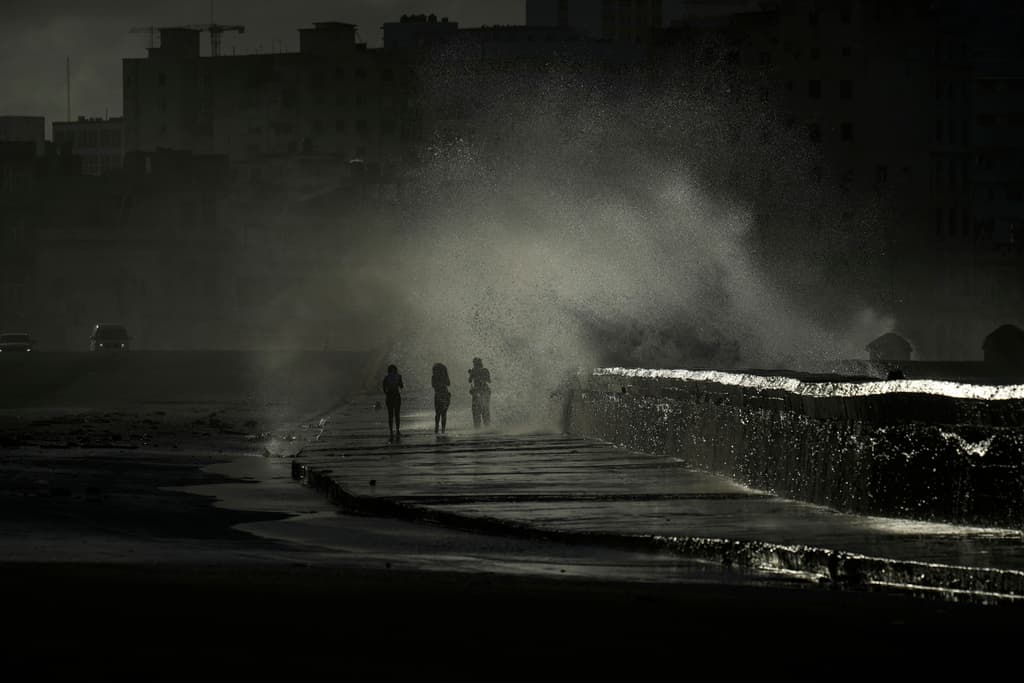 Varias personas caminando por el malecón en medio de la oscuridad.