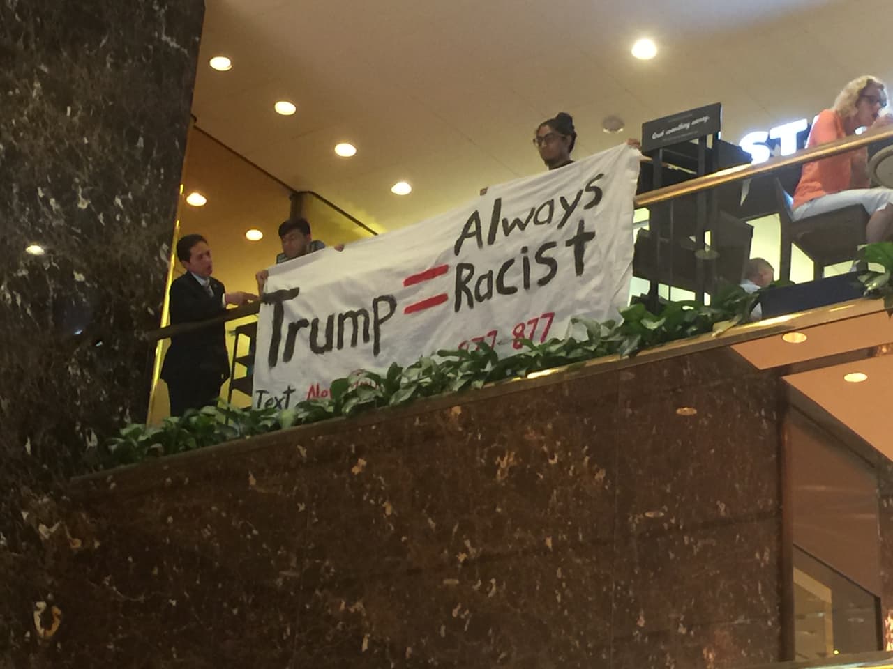 El momento en el que los hispanos cuelgan su pancarta dentro de la Torre Trump.