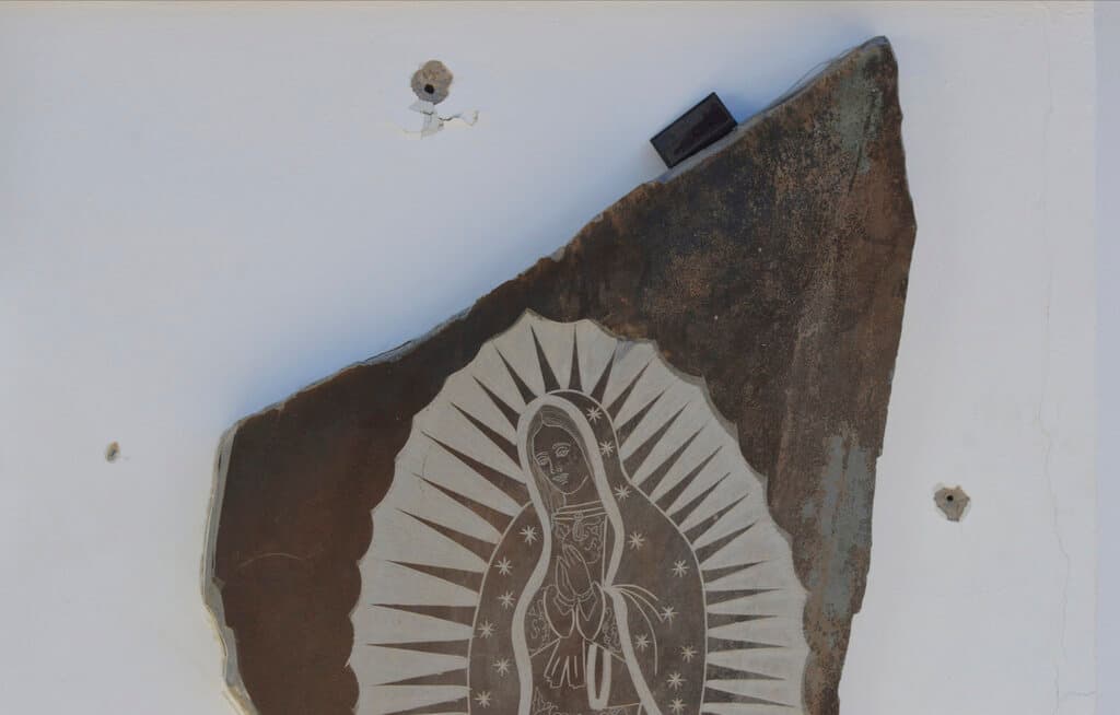 Los impactos de bala marcan una pared de la casa decorada con una imagen de la Virgen de Guadalupe. La detención de Ovidio Guzmán sorprendió al ocurrir días antes de 
<a href="https://www.univision.com/noticias/inmigracion/biden-visita-el-paso-texas-tras-cambio-politica-asilo-frontera" target="_blank">la visita a México del presidente estadounidense, Joe Biden</a>, con motivo de la Cumbre de Líderes de América del Norte. El presidente Andrés Manuel López Obrador, sin embargo, negó cualquier relación entre los dos hechos.