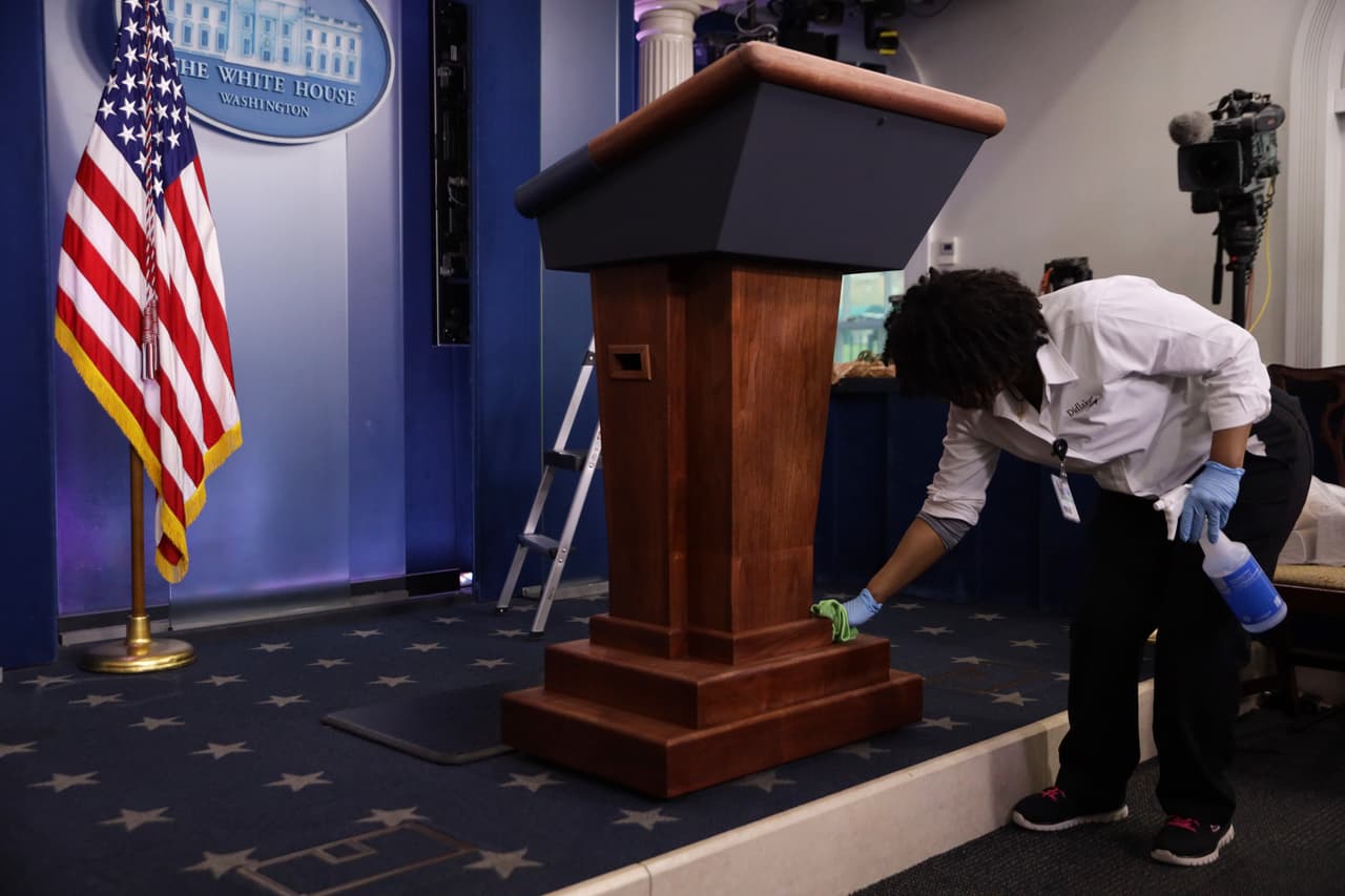 <b>Protección para todos.</b> Una trabajadora de la Casa Blanca se ocupa de dejar bien limpio el podio de la sala de prensa, desde donde se han encontrado con. Los medios las autoridades sanitarias del país y el presidente Trump.