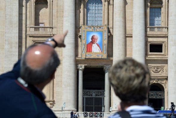 Turistas observan los tapices de los papas que serán canonizados el domingo 27 de abril.