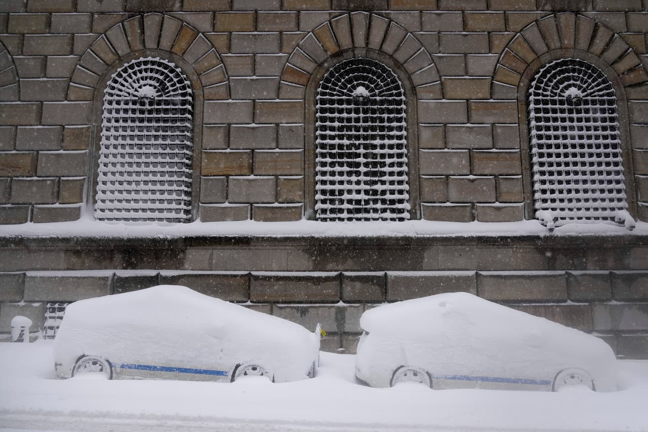 Vehículos urbanos estacionados cubiertos de nieve en el bajo Manhattan durante una tormenta de nieve.