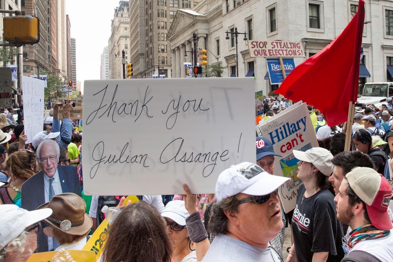 LUNES 25 DE JULIO. 3:27 PM. La concentración de los seguidores de Bernie Sanders continúa en el centro de Filadelfia, esperan su presentación esta tarde en la convención. En uno de los carteles que lleva un manifestante se lee “gracias Julian Assange”, en clara alusión al escandalo de los correos del partido demócrata filtrados por Wikileaks.