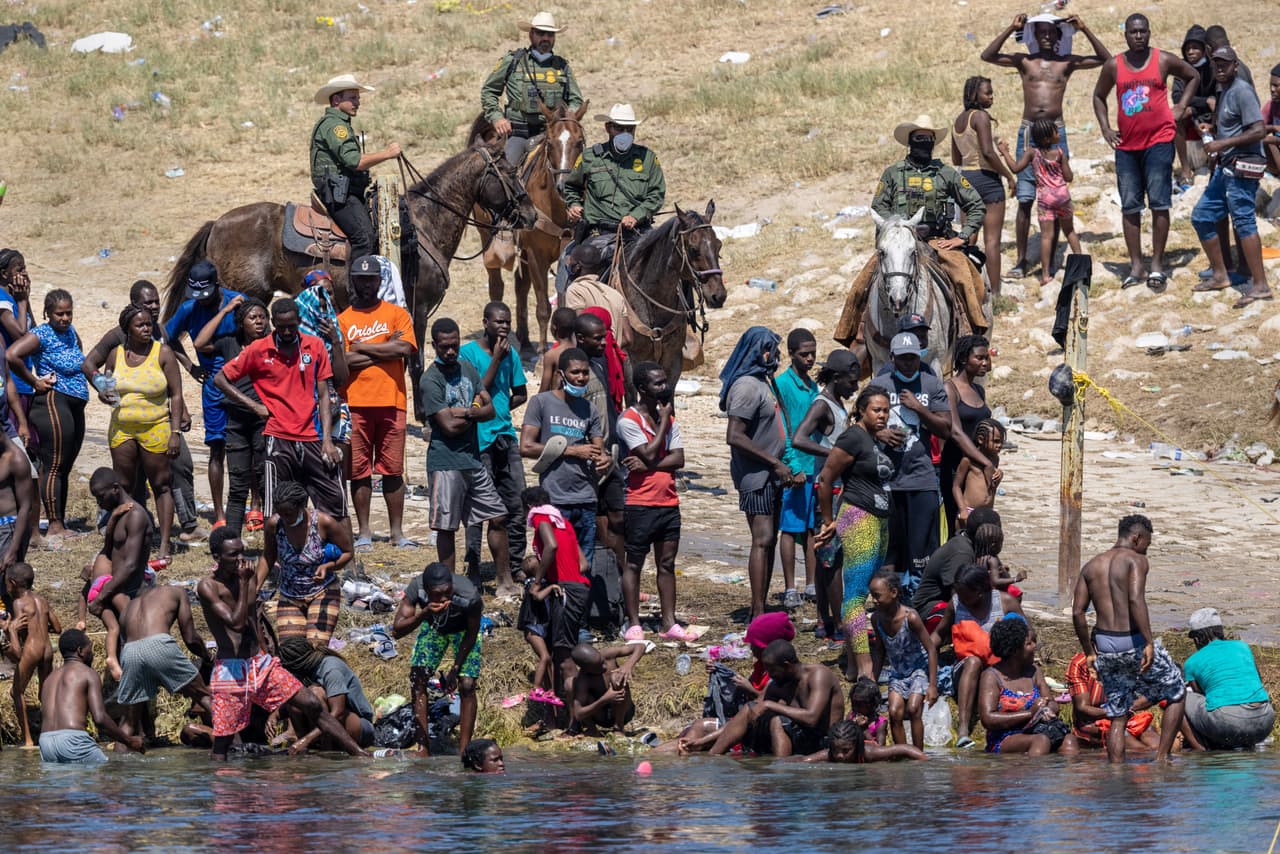 Agentes de la Patrulla Fronteriza de Estados Unidos montados observan a los inmigrantes haitianos en la orilla del Río Grande en Del Río, Texas, el 20 de septiembre de 2021, visto desde Ciudad Acuña, México.