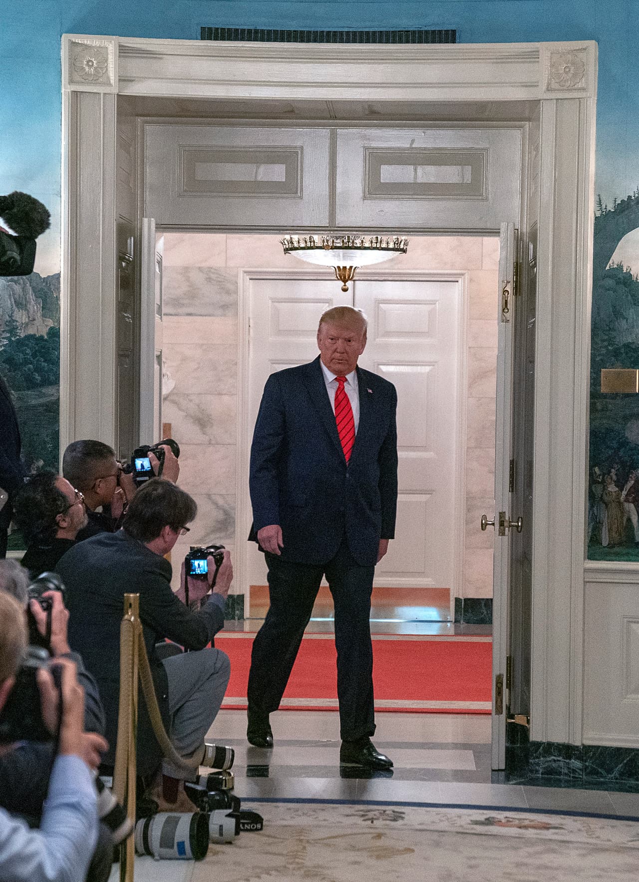 El presidente Trump ingresa a la Sala de Recepción Diplomática de la Casa Blanca para ofrecer detalles de la operación militar que terminó con la inmolación de Baghdadi. Dijo que los primeros días de la semana pasada supieron de la ubicación del líder de EI y que tomaron la decisión de llevar a cabo la operación este sábado. Explicó que uno de los helicópteros recibió disparos y respondieron "para eliminar la amenaza". Agregó que al menos dos yihadistas fueron capturados y 11 niños fueron hallados en el lugar.