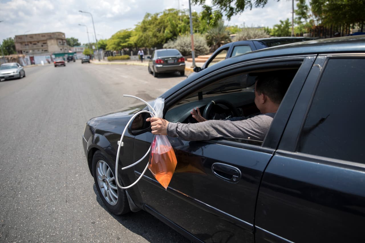 Un hombre sale de una estación de gasolina con una bolsa de combustible extra en Cabimas,en el oeste de Venezuela, donde la crisis de combustible se incrementó a mediados de año.
<a href="https://www.univision.com/noticias/america-latina/por-que-el-alza-de-los-precios-del-petroleo-beneficia-poco-al-pais-con-las-mayores-reservas-del-mundo">Más de cuatro millones de venezolanos han abandonado el país</a> en los últimos años para escapar de la crisis económica, hospitales que no funcionan, servicios básicos en decadencia y falta de seguridad. El control del gobernante
<a href="https://www.univision.com/noticias/crisis-en-venezuela/en-la-batalla-de-presidentes-en-venezuela-cuanto-tiempo-puede-resistir-maduro">Nicolás Maduro se ve desafiado por el opositor Juan Guaidó</a>, que fue respaldado por más de 50 países.