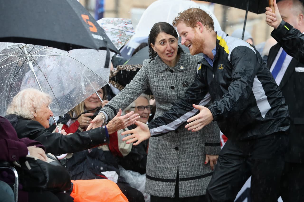 Bajo una torrencial lluvia, miles de personas esperaron para tan solo saludar a la lejanía al Príncipe Harry durante su última visita a Australia.