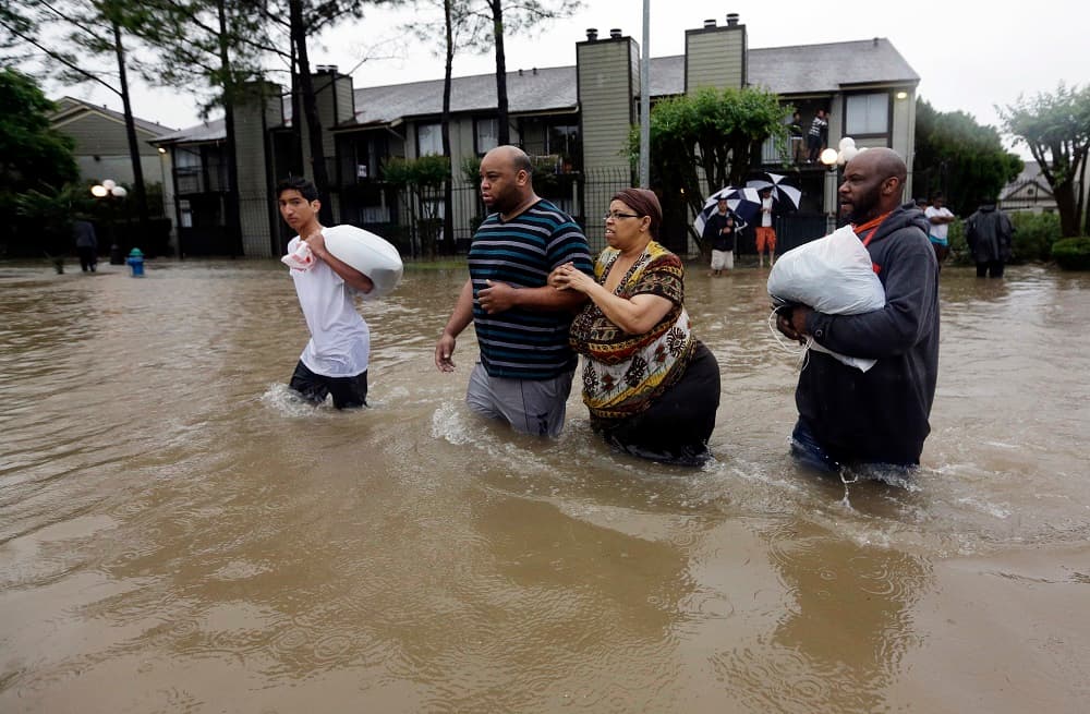 Darius Simon (segundo por la izquierda) ayuda a su madre a evacuar su apartamento inundado por las fuertes lluvias