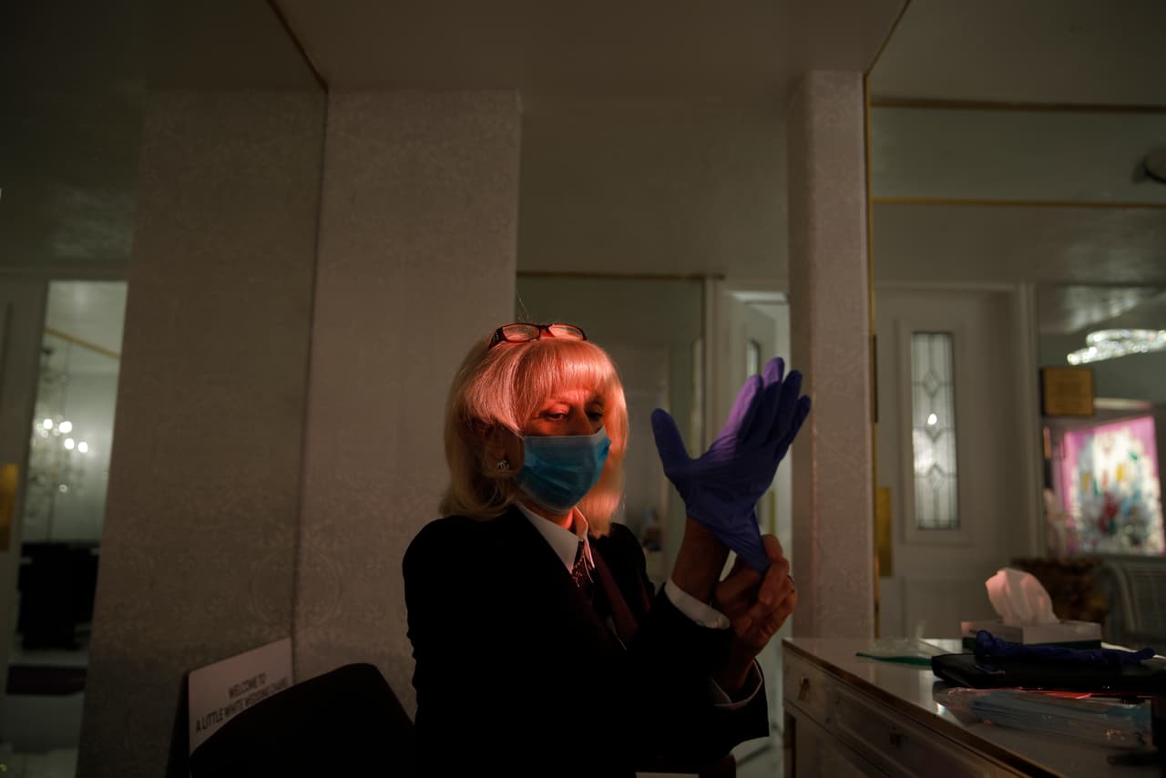 Eunice Weisbart se pone el equipo de protección contra el coronavirus antes de oficiar una boda en A Little White Wedding Chapel. 
<b>"No podemos evitar que la vida continúe"</b>, aseguró.
<br>