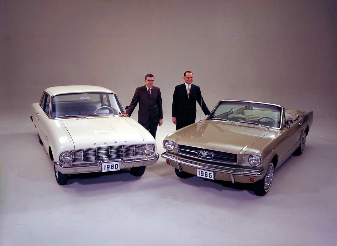 En esta imagen se puede ver nuevamente a Lee Iacocca y a Don Frey junto al nuevo 
<b>Ford Mustang</b> junto a su donante mecánico el 
<b>Ford Falcon</b>. El Mustang y el Falcon fueron dos fenómenos de ventas sin precedentes hasta el momento y muy pocas veces superados desde entonces.
