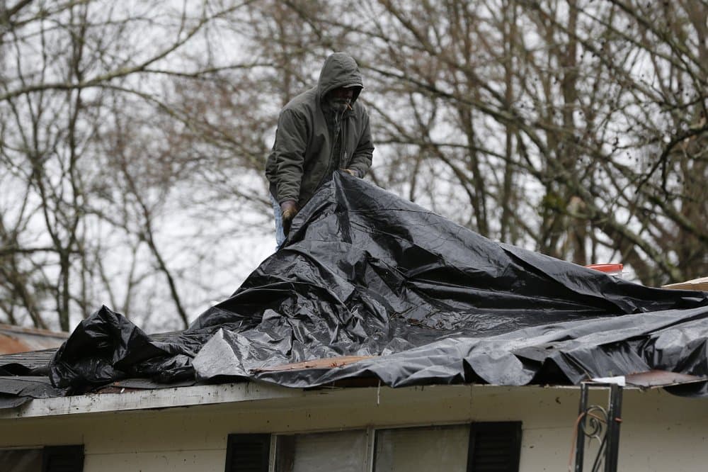 Un trabajador pone una lona sobre el tejado de una casa que resultó afectada por la tormenta en Pickens, Mississippi.