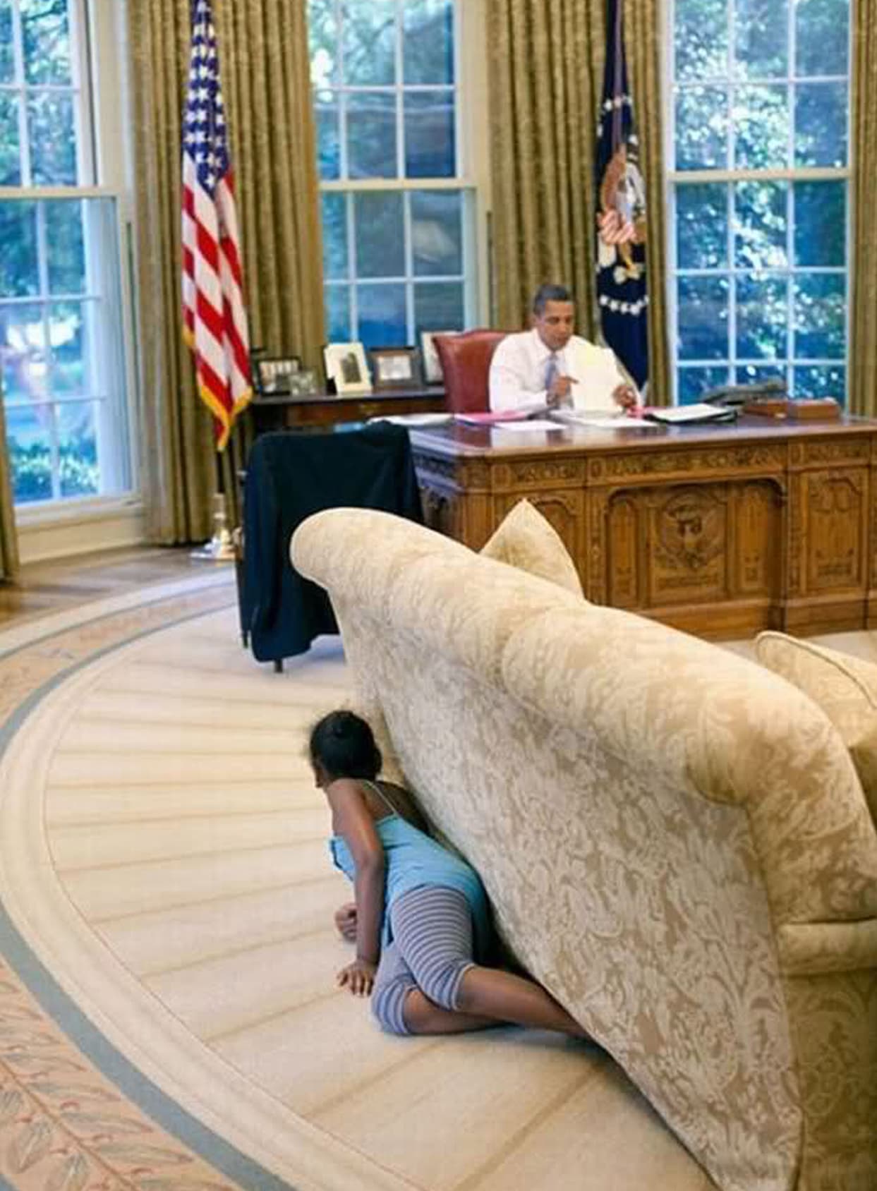 Sasha, la hija menor del presidente Barack Obama, se esconde detrás y debajo del sofá de la oficina de su padre. 2009.