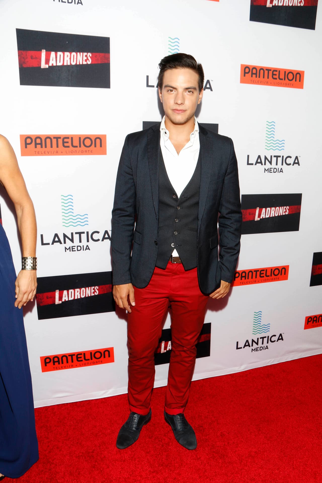 Vadhir muy formalito con pantalones rojos y saco oscuro.