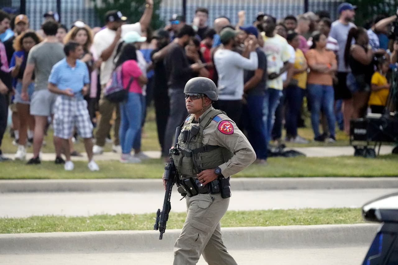 Un oficial de la ley lleva un rifle mientras las personas son evacuadas del centro comercial Allen Premium Outlets donde ocurrió un tiroteo el sábado 6 de mayo de 2023 en Allen, Texas.