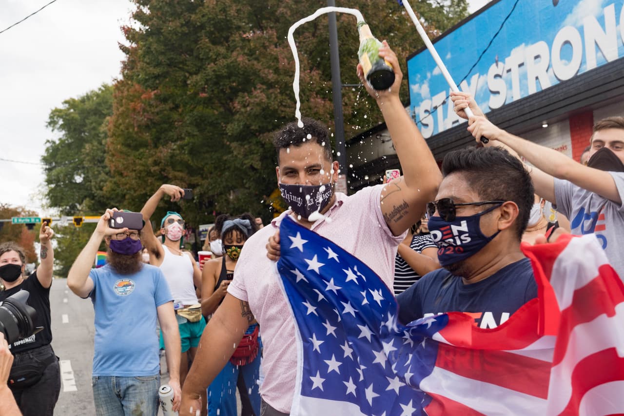 Simpatizantes de Biden celebran con la bandera estadounidense el triunfo en las elecciones presidenciales 2020.