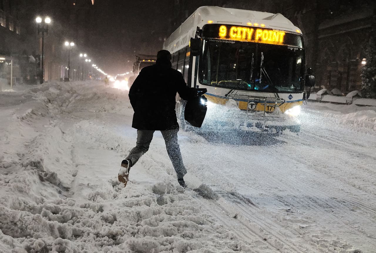 Un hombre corre para tomar el autobús en una calle nevada de Boston, Massachusetts.