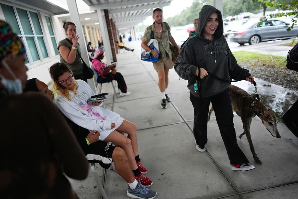 <b>Protege a su mascota: </b>Una mujer camina con su perro afuera de la escuela secundaria Gibbs, un refugio del gobierno donde 1700 personas ya habían buscado refugio a última hora de la mañana del miércoles 9 de octubre de 2024, antes de la llegada del huracán Milton a San Petersburgo, Florida.