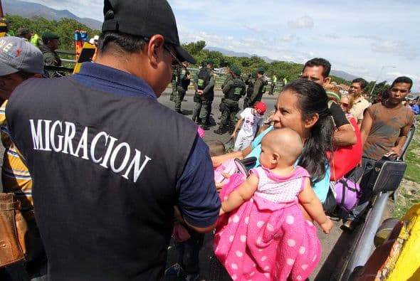 Una mujer lleva a su hija ante un agente de inmigración para mostrar su identificación y poder ingresar al país.