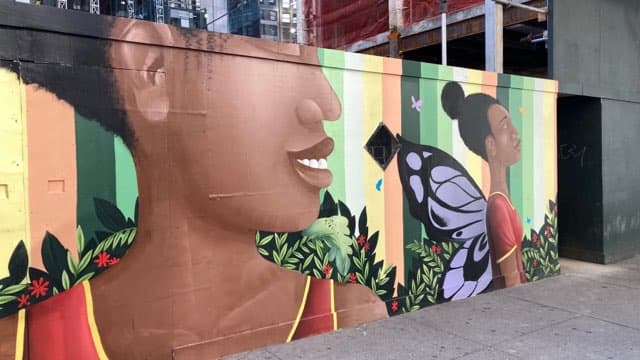 Los rostros en el mural sonríen, miran al cielo o tienen alas.