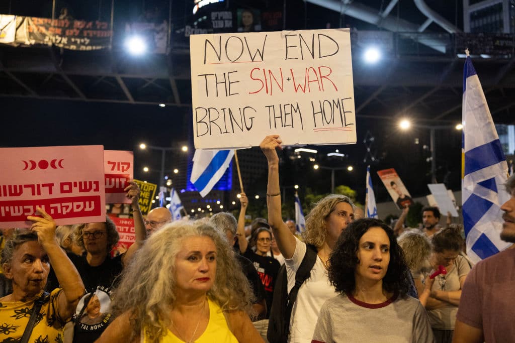 Supporters and relatives of Israelis held hostage by Palestinian militants in Gaza since the October 7 attacks, hold placards and wave national flags during a demonstration calling for their release, outside the Ministry of Defence in Tel Aviv on October 17, 2024. Israel announced on October 17 the killing of Hamas chief Yahya Sinwar, mastermind of the October 7 attack, calling his death a "heavy blow" to the Palestinian group it has been fighting for more than a year. (Photo by Oren ZIV / AFP) (Photo by OREN ZIV/AFP via Getty Images)