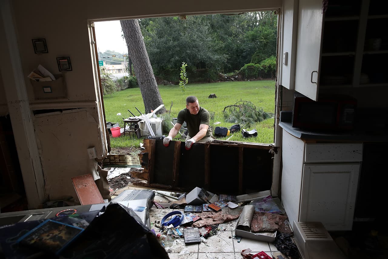 Derek Pelt quita una pared entera de la casa de su amigo Bryan Parson en Houston, severamente afectada por la inundación.