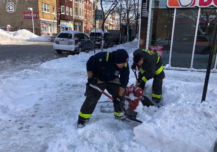 Los bomberos de Chicago desenterrando de nieve la salida de agua.