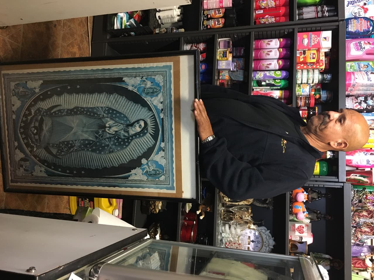 Jaime Vallejo, dueño de una mercería en el Este de Los Ángeles, sostiene el cuadro de la Virgen que –según él- lo ha protegido de los ladrones durante muchos años.