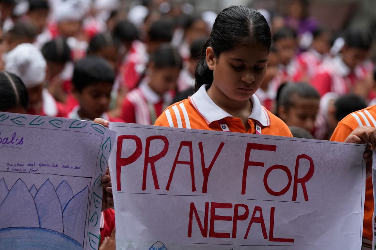 Niños de una escuela sostienen pancartas mientras ofrecen oraciones especiales por las víctimas de las inundaciones repentinas en Nepal, en Jammu, India, el sábado 29 de agosto de 2026.