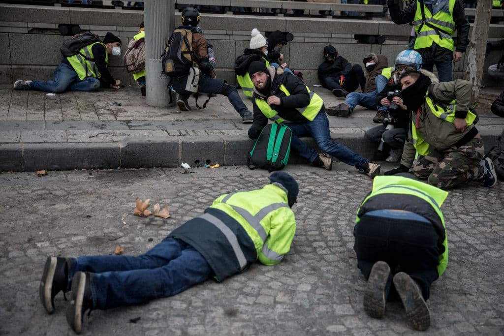 Integrantes del movimiento de los 'chalecos amarillos' se cubren luego de que la policía les arrojara gas lacrimógeno.