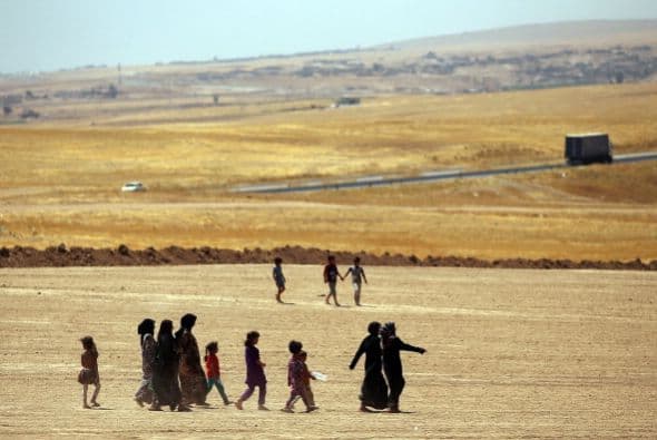 Mujeres y niños iraquíes caminan hacia una entrada en un campamento de refugiados.