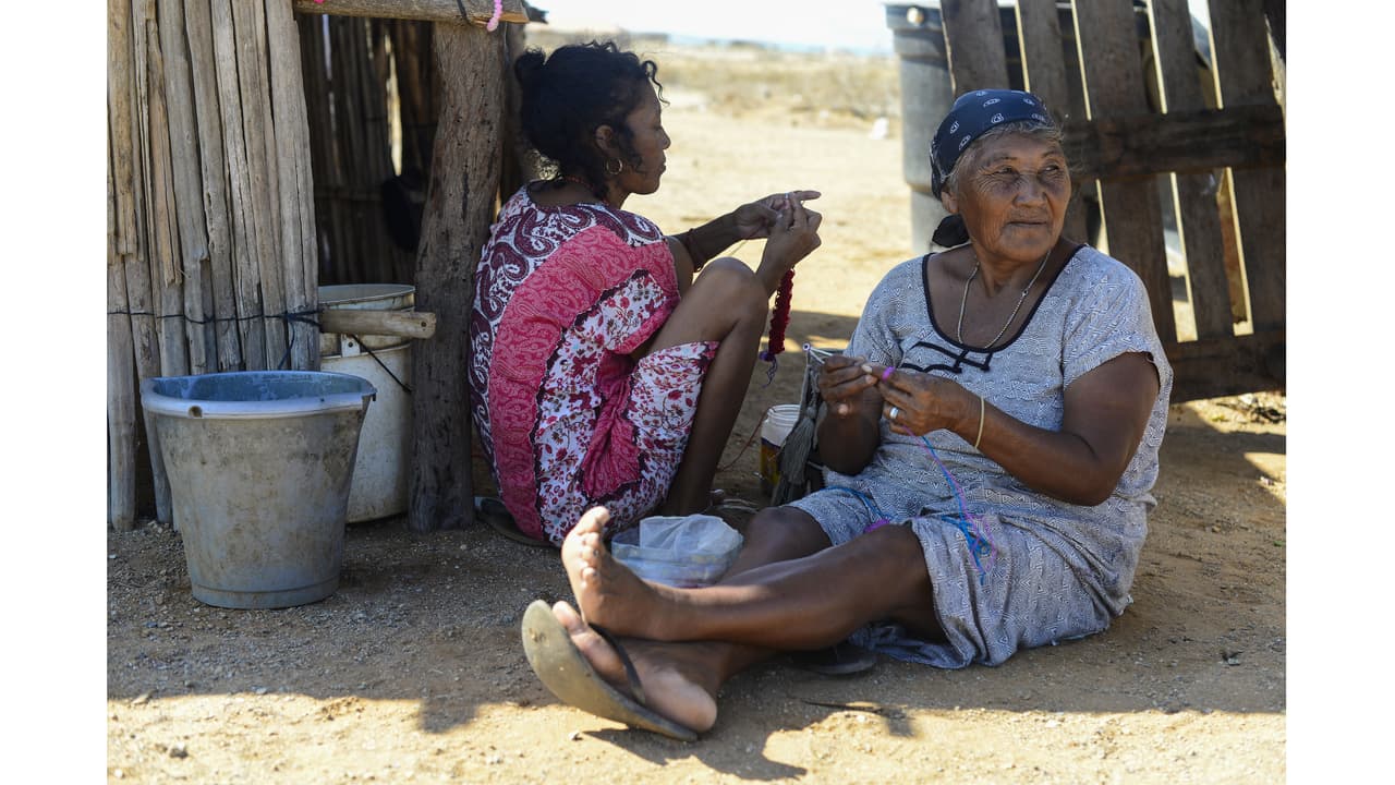 Mujeres Wayúu tejen bolsos para vender en Cabo de la Vela. Tradicionalmente los Wayuú no vendían sus artesanías, pero como no pueden cultivar sus alimentos, muchas comunidades se han lanzado al turismo en busca de dinero.