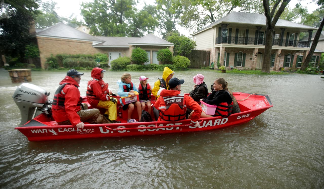 Un bote de la Guardia Costera con víctimas de las inundaciones navega por una calle de un vecindario de Houston.