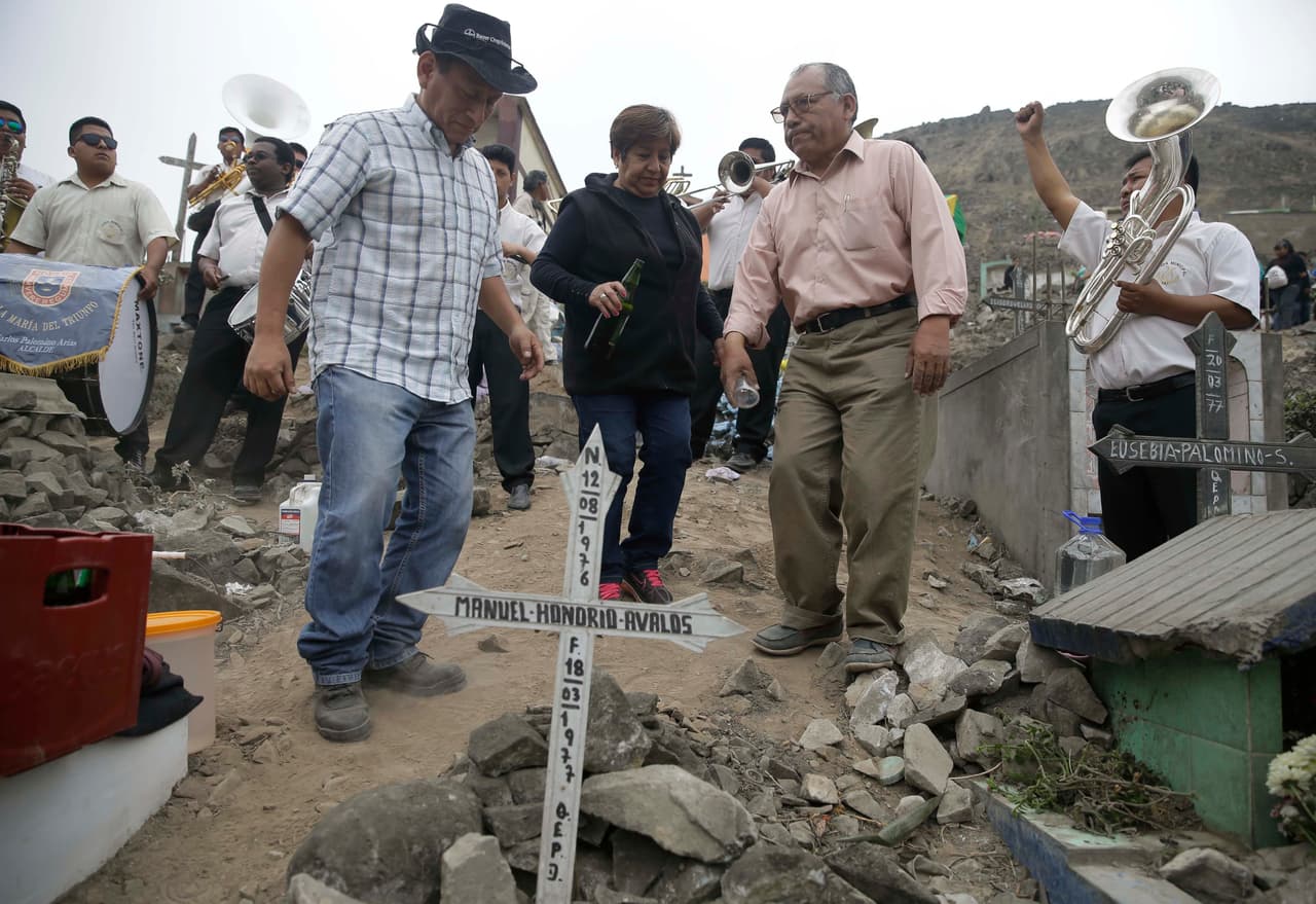 <b>Perú. </b>Miembros de una familia bailan y beben junto a la tumba de un pariente en el cementerio Nueva Esperanza de Lima, en una visita alegre a sus familiares fallecidos.