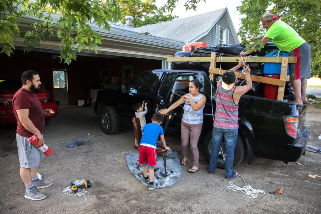 Miguel Hernandez, left, talks with his wife, Luisa Tepole, about what to load into their pickup truck as they prepare to return to their hometown in Mexico. His cousin, Eric Hernandez, and co-worker Pedro Tepole, right, help to load the truck a little after 8 p.m. on May 31, 2017. Miguel and Pedro had already worked a full-shift on the Knoepke's dairy farm in Pepin County, Wis.