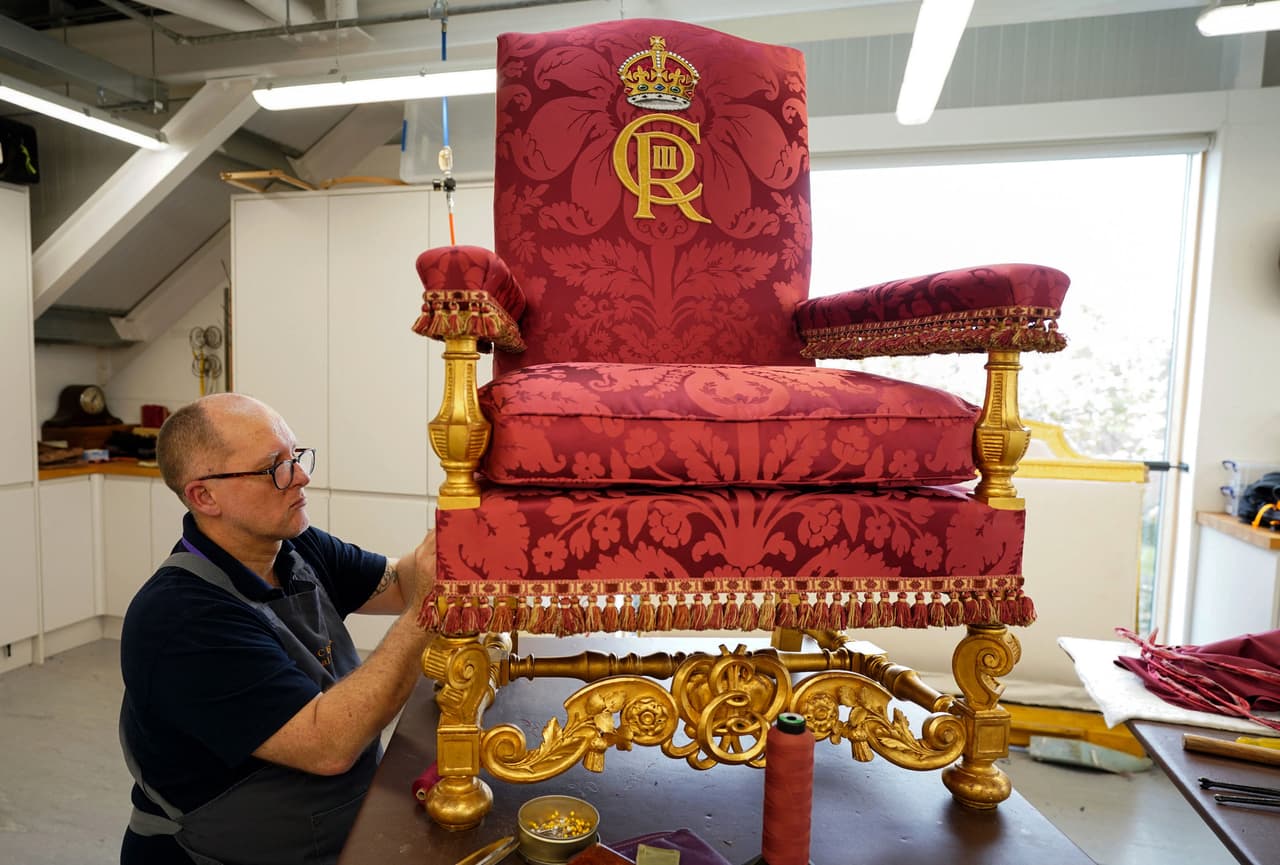 Un trabajador de la Casa Real prepara la silla de Estado que se usará durante la coronación del rey Carlos III, en una fotografía del 21 de abril de 2023.