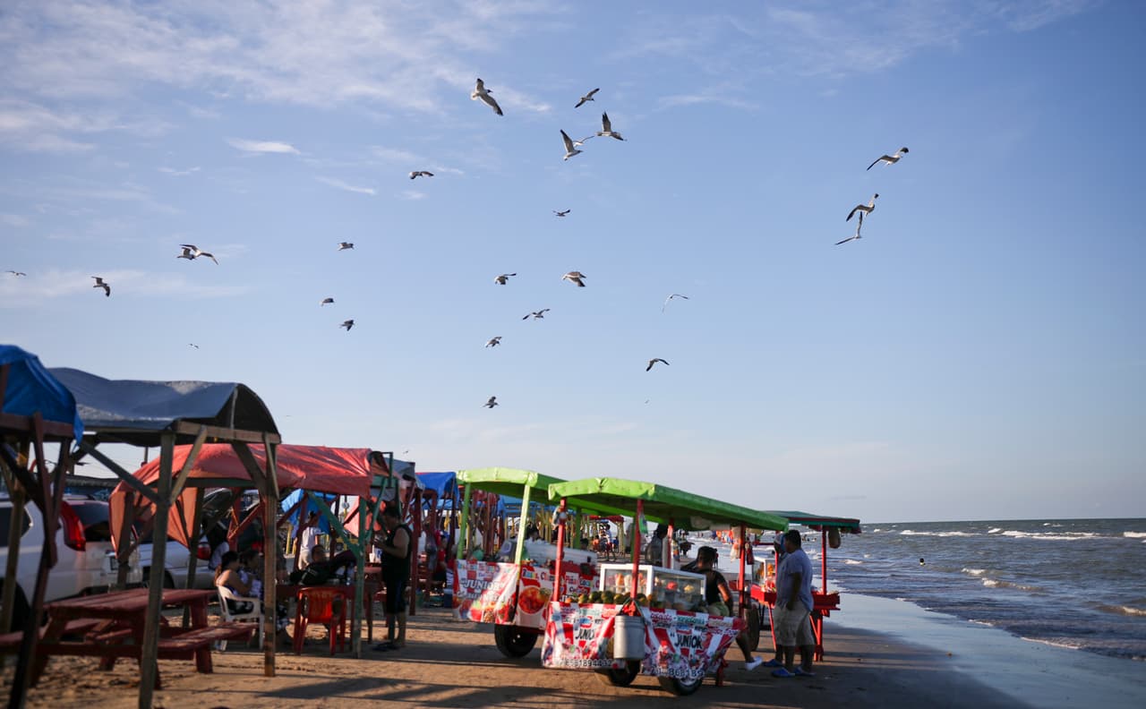 Las gaviotas sobrevuelan los puestos de comida en Playa Bagdad. Unas pocas millas al norte desemboca el Río Bravo (o río Grande para los estadounidenses), el serpenteante límite natural que divide México de EEUU en una extensión de 1,885 millas.
<a href="https://www.univision.com/noticias/inmigracion/en-estos-lugares-la-naturaleza-interrumpe-al-muro-fronterizo-fotos-fotos">A diferencia de la frontera en la costa del océano Pacífico</a>, aquí no hay barras de hierro que se meten en el mar para evitar el cruce de indocumentados. Los miles de migrantes que cruzan México para buscar asilo en EEUU y se acumulan en otros puntos al oeste no se acercan a esta playa.