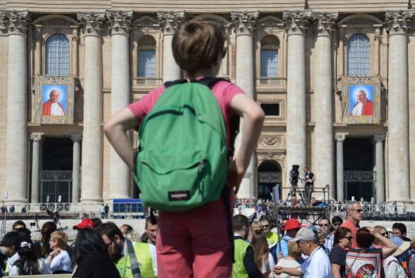 Un niño mira los tapices de Juan Pablo II y Juan XXIII (i) que cuelgan de los balcones de la Basílica de San Pedro.