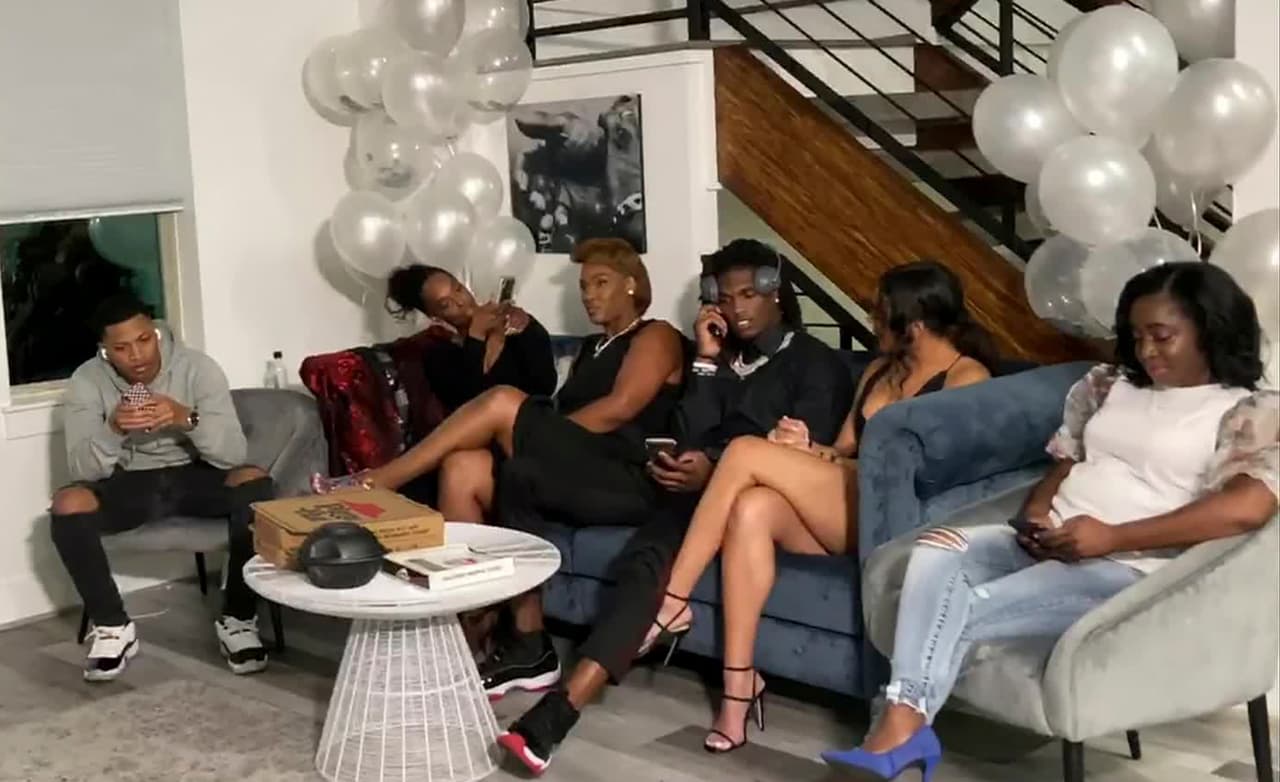 In this still image from video provided by the NFL, CeeDee Lamb, third from right, talks on a phone in Houston during the NFL football draft Thursday, April 23, 2020. Lamb was chosen by the Dallas Cowboys in the first round. (NFL via AP)