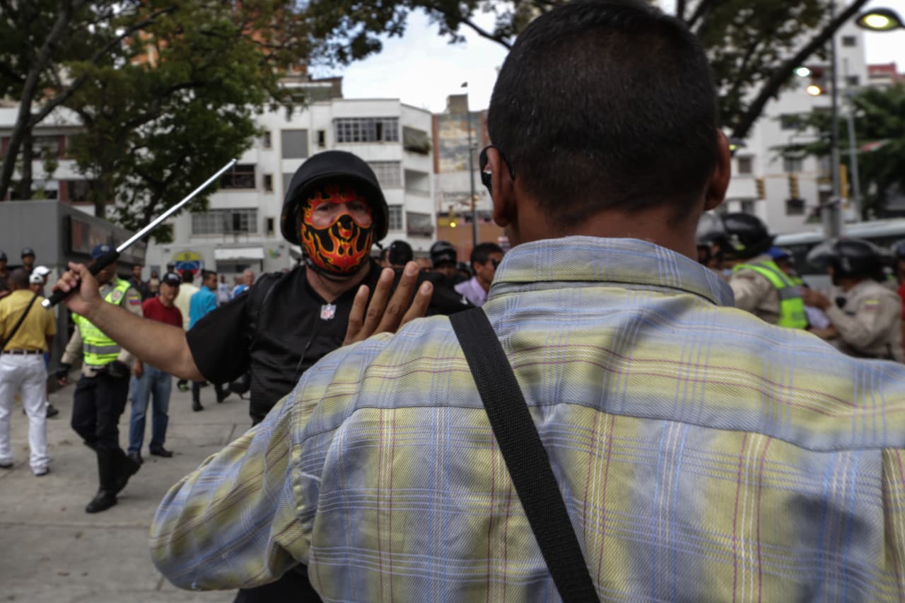 Un encapuchado, identificado por los testigos como miembro de un 'colectivo', agrede a manifestantes opositores frente al ministerio público en el centro de Caracas el 31 de marzo de 2017. Defensores de Derechos Humanos y partidos de oposición alertan que estas bandas paramilitares ejecutan las operaciones represivas ordenadas por el gobierno.
<br>