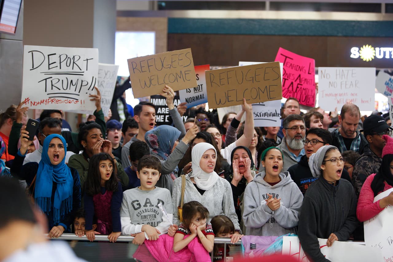 Los mensajes de estas pancartas en la zona de llegadas del aeropuerto de Dallas en Texas: "Deporten a Trump #NotMyPresident" y "Los refugiados son bienvenidos".