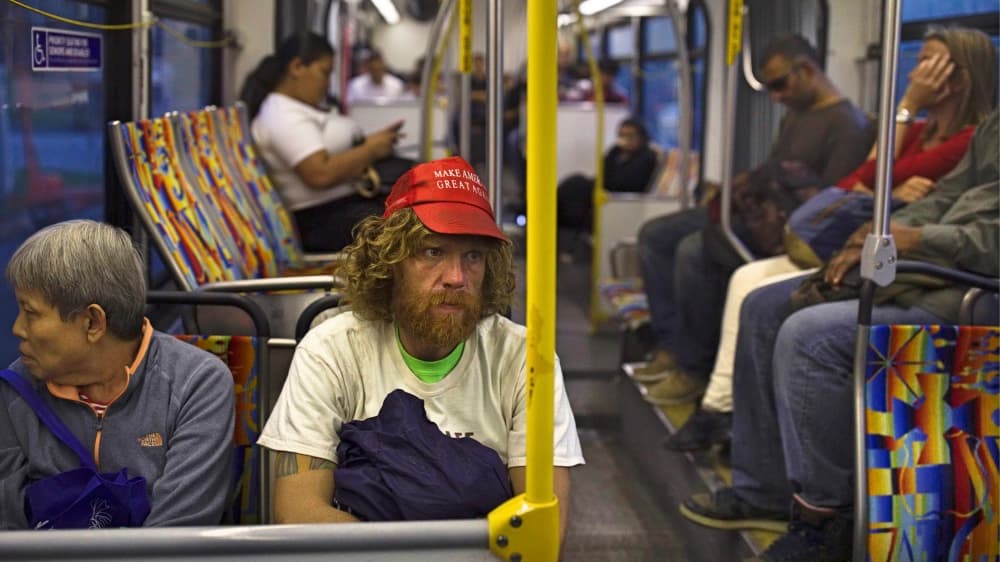 Portando una gorra con el lema presidencial de Donald Trump 'Make America Great Again', Nathanael Baisley, de 38 años, viaja en un autobús de Los Ángeles a Santa Mónica para pasar la noche en la playa.