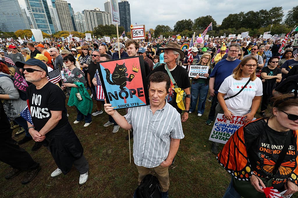 <b>Marea humana en Grant Park. </b>Miles de manifestantes se congregan al mediodía en Grant Park, ondeando pancartas coloridas con mensajes en defensa de la democracia. El sol del mediodía ilumina las banderas estadounidenses y los carteles que exigen libertad y respeto a los derechos civiles.