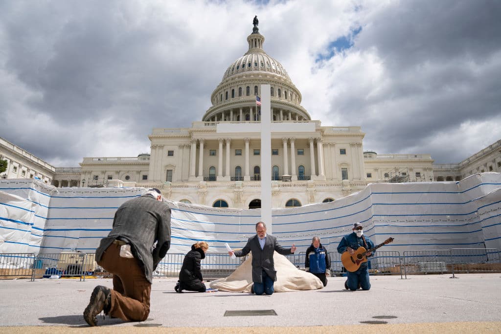 A pesar del riesgo que significa estar en las calles, el reverendo Patrick Mahoney, director de la Christian Defense Coalition, se arrodilla en oración mientras transmite en vivo un servicio del Viernes Santo frente al Capitolio, en
<b>Washington DC.</b>