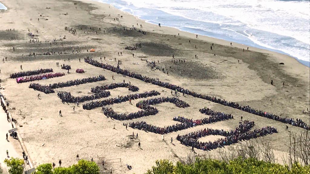 Cientos de personas forman la palabra "resistencia" en una playa de San Francisco durante una protesta contra Trump