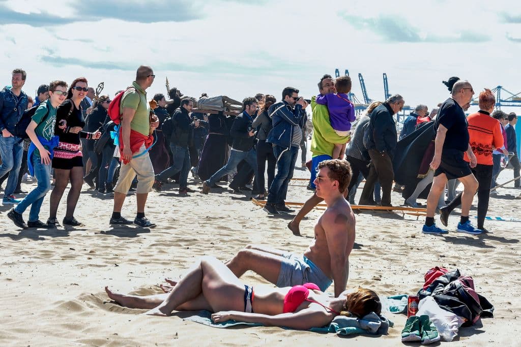 Penitentes de la hermandad de Cristo Salvador y del Amparo cargan un crucifijo junto a varios turistas en su peregrinación de Viernes Santo en Valencia, España.