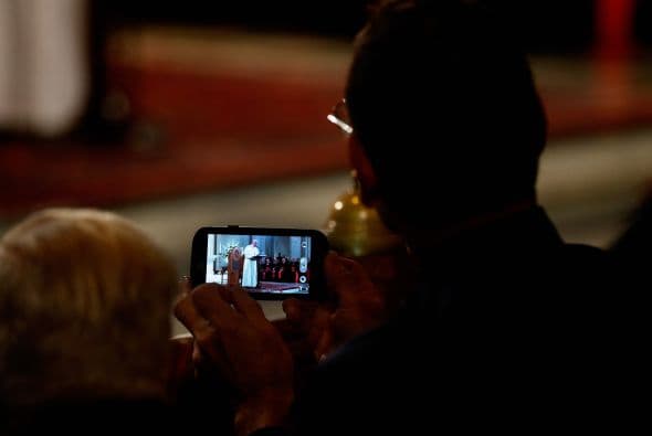Este hombre mira al pontífice a través de su teléfono móvil.