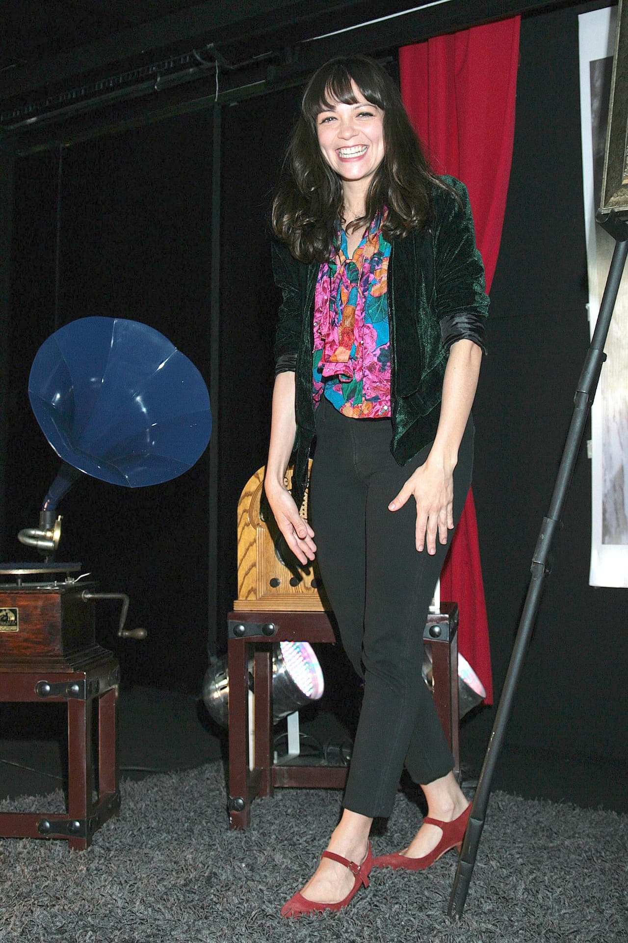 De gran sonrisa, su vestuario también ilumina su look: camisa floreada, tonos negros y un melena en tono negro oscuro.